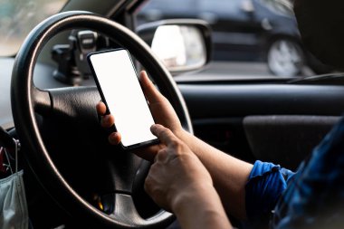Direksiyonun arka planına karşı bir cep telefonu. Resim Taşımacılığı ve Araç GPS kavramları koymak için beyaz ekranlı bir telefon.