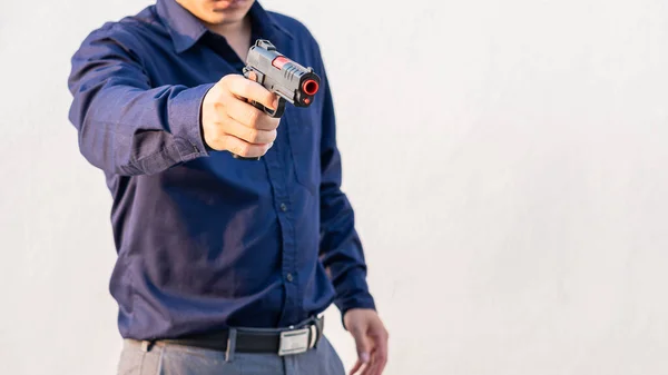 Mladý Asiat Modré Košili Drží Ruce Pistoli Bílé Pozadí — Stock fotografie