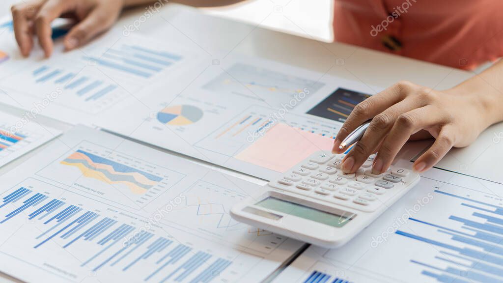 An accountant, businessman or finance professional analyzes graphs, business reports and financial charts at the Office of Financial Economics Concepts.