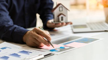 Bir emlak işadamı, Waqah. Ofisteki masada dizüstü bilgisayarı olan bir şirket maliyet grafiği..