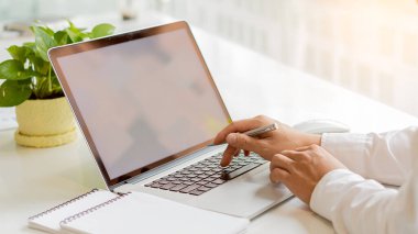 Uzaktan kumandayla çalışan bir iş adamının sosyal ağlarla iletişim kuran ahşap bir masada oturup internetten bilgi ararken yan görüntüsü..