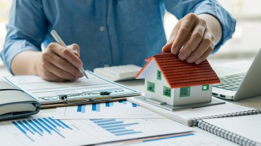 Emlak İşadamı, Ev Satış Ajanı Kraah, modern dizüstü bilgisayarları ve hesap makineleri olan gelir tabloları ve grafikler. Stratejik kavram