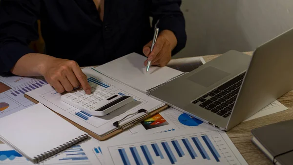 Business people doing business in finance and calculating on investment costs, real estate and more, tax system with laptop and table top graph.