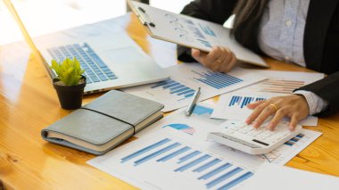 Hesaplamalarla notlar yazmak için bir hesap makinesi kullanan yakın plan iş adamları, mali muhasebe kavramları üzerinde grafik analizi.