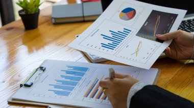 Hesaplamalarla notlar yazmak için bir hesap makinesi kullanan yakın plan iş adamları, mali muhasebe kavramları üzerinde grafik analizi.