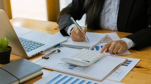 Hesaplamalarla notlar yazmak için bir hesap makinesi kullanan yakın plan iş adamları, mali muhasebe kavramları üzerinde grafik analizi.