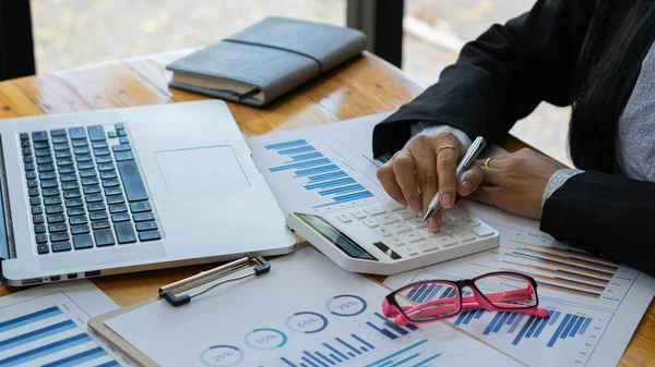 Hesaplamalarla notlar yazmak için bir hesap makinesi kullanan yakın plan iş adamları, mali muhasebe kavramları üzerinde grafik analizi.