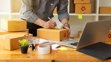 İşe yeni başlayan küçük işletme sahipleri, dizüstü bilgisayarlar ve hesap makineleri ile iş yerinde karton kutular, küçük işletme girişimcileri, KOBİ 'ler evde kutularla çalışıyor, çevrimiçi, e-ticaret.