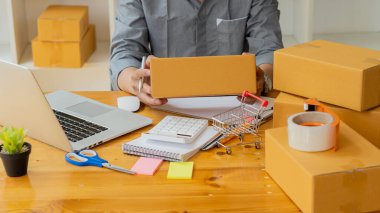 İşe yeni başlayan küçük işletme sahipleri, dizüstü bilgisayarlar ve hesap makineleri ile iş yerinde karton kutular, küçük işletme girişimcileri, KOBİ 'ler evde kutularla çalışıyor, çevrimiçi, e-ticaret.