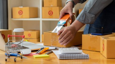 İşe yeni başlayan küçük işletme sahipleri, dizüstü bilgisayarlar ve hesap makineleri ile iş yerinde karton kutular, küçük işletme girişimcileri, KOBİ 'ler evde kutularla çalışıyor, çevrimiçi, e-ticaret.
