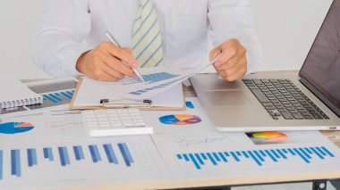 İş adamlarının elinde grafiklere, grafiklere, finansmana dikkat çekmek ve iş başarısı planlama süreçlerini analiz etmek ve hesaplamak için bir kalem var..