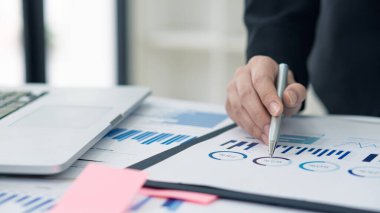 Genç işadamları şirket stratejisi planlamada grafikler ve dizüstü bilgisayarlar kullanarak verileri analiz ederler..