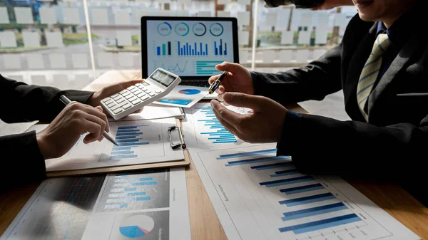 Business people doing business in finance and calculating, analyzing, graphing on costs of investments, real estate and more, tax system on the desk with laptops and calculators with documents.