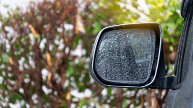 Arka planda yağmur damlaları olan aynanın sol tarafı bulanık..
