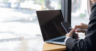 İş kadınları cep telefonları ve dizüstü bilgisayarlarla çalışır