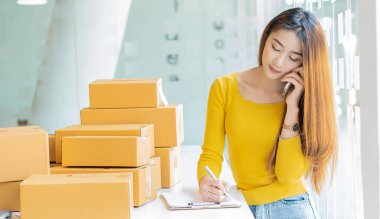 Dizüstü bilgisayarlar ve telefonlar ile çalışan küçük işletme sahipleri, iş yerinde cep telefonu ve karton kutular, küçük işletme girişimcileri, evdeki kutularla çalışan KOBİ, çevrimiçi satış, e-ticaret.