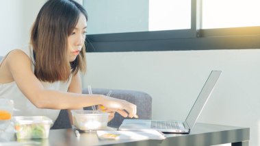 Genç kadınlar evde çalışır ve işleri sırasında yemek yerler..