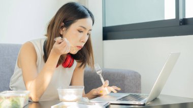 Genç kadınlar evde çalışır ve işleri sırasında yemek yerler..