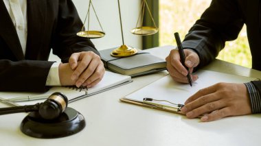 Avukatlar ve danışmanlar ofiste çalışıyor. Önlerine bir yargıç çekici ve adaletsizliğin altın pulları yerleştiriliyor..