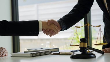 Avukat Danışman İşadamı, yargıç çekiciyle ofiste el sıkışıyor ve adalet terazisi dizüstü bilgisayar avukatı kavramı ve hukuki danışmanlık kavramı ile işliyor.