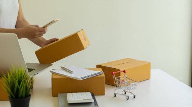 Küçük işletme sahipleri iş yerlerinde dizüstü bilgisayarlar ve karton kutularla çalışıyorlar. Küçük işletme girişimcileri KOBİ 'ler evlerinde kutu kutu satarak online e-ticaret yapıyorlar.