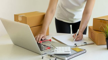 Küçük işletme sahipleri iş yerlerinde dizüstü bilgisayarlar ve karton kutularla çalışıyorlar. Küçük işletme girişimcileri KOBİ 'ler evlerinde kutu kutu satarak online e-ticaret yapıyorlar.