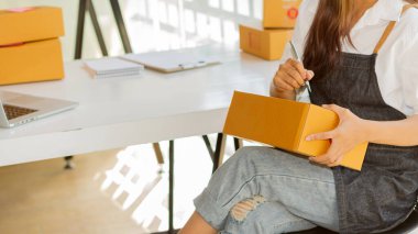 Küçük işletme sahipleri iş yerlerinde dizüstü bilgisayarlar ve karton kutularla çalışıyorlar. Küçük işletme girişimcileri KOBİ 'ler evlerinde kutu kutu satarak online e-ticaret yapıyorlar.