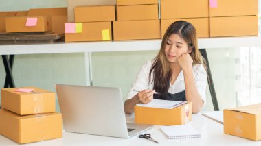 Küçük işletme sahipleri iş yerlerinde dizüstü bilgisayarlar ve karton kutularla çalışıyorlar. Küçük işletme girişimcileri KOBİ 'ler evlerinde kutu kutu satarak online e-ticaret yapıyorlar.
