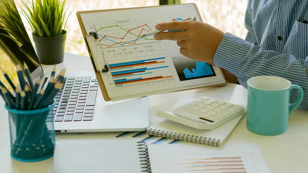 Business people doing business in finance and calculating, analyzing, graphing on costs of investments, real estate and more, tax system on the desk with laptops and calculators with documents