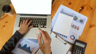 Kendinden emin genç bir işadamı grafik verilerini analiz eder ve hesap makinesiyle hesaplar ve ofisteyken bilgisayar kullanır..