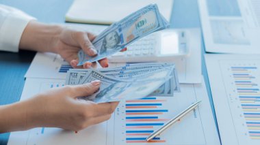 Bir avuç dolusu Amerikan doları insan elinde. Masada hesap makinesi olan iş ve nakit