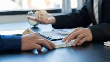 Emlakçılar, ev tasarımları ve satın alma sözleşmelerini görmek için onlarla iletişime geçen müşterilere ev tasarımları öneriyorlar. Ofisin içinde.