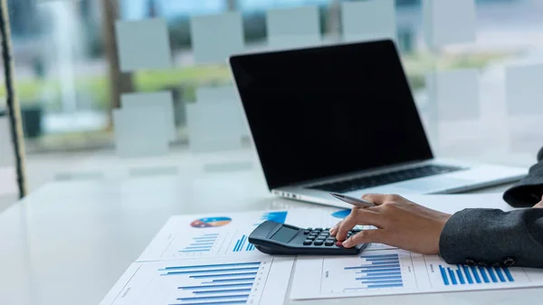 Business people doing business in finance and calculating, analyzing, graphing on costs of investments, real estate and more, tax system on the desk with laptops and calculators with documents