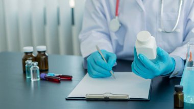 Elinde ilaç şişesi olan bir doktor ofisine reçete ve bir şişe aşı yazmış..