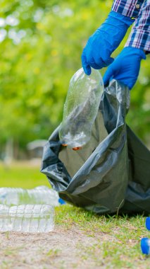 Adam halka açık bahçede temizlik yapmak için plastik şişe topluyor. Çevre için atık toplamaya yardım