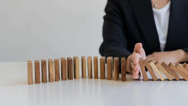 risk control concept A businessman defends a falling wooden block and a construction business risk strategy to select and protect the wooden blocks that line up on the table.
