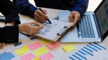 İş adamları, başarı sürecini planlama stratejilerini gösteren grafikleri ve finansal grafikleri analiz eder ve hesaplar.