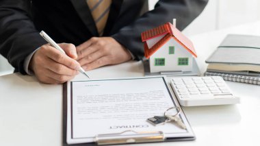 Emlakçı ev satın alma anlaşmasından bahseder ve müşteriden yasalara uyması için bir sözleşme yapmasını ister..