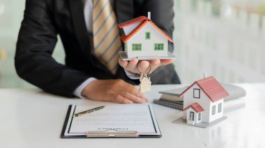 Emlakçı ev satın alma anlaşmasından bahseder ve müşteriden yasalara uyması için bir sözleşme yapmasını ister..