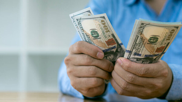Бизнесмен считает американские доллары вручную. Концепция доходов и бизнеса.