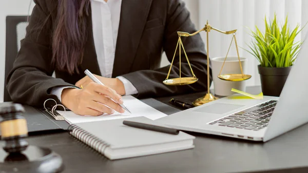 Consulting of business women and male lawyers or judges counselors. Legal services concept with judge's hammer and golden scales with laptop on table.