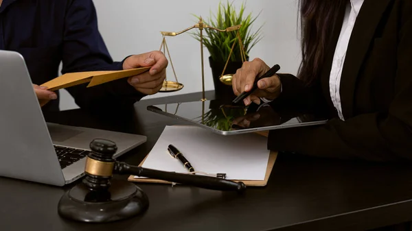 Consulting of business women and male lawyers or judges counselors. Legal services concept with judge\'s hammer and golden scales with laptop on table.