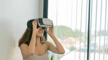 Genç bir kadın evde mutlu bir şekilde film izlemek için 3D gözlük takıyor..