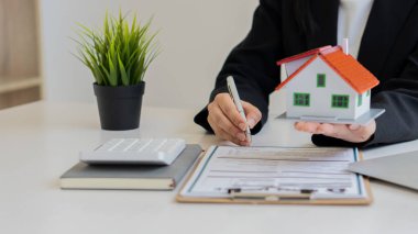 Emlak komisyoncuları, konutlar, kira sözleşmeleri ve iş yeri evin mimari tasarımından sonra bir sözleşme imzaladı. Ofiste ev satışları ve kiralama fikirleri ve masadaki dizüstü bilgisayar..