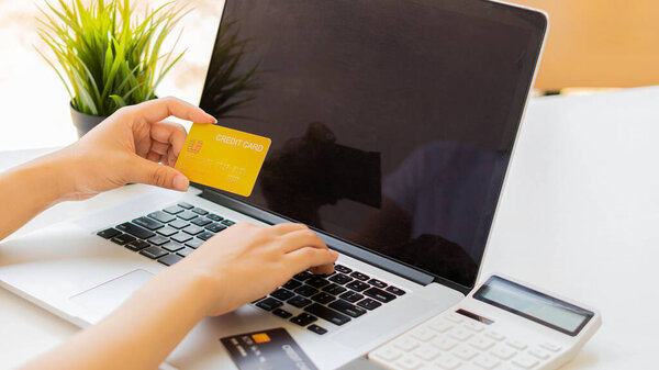 Hold a credit card and a phone while shopping online and pay online via the internet.Use a credit card with a laptop.