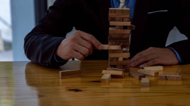 Proje yönetimi, işadamları ve mühendislerin planlama, risk ve stratejisi. Tahta kule blokları yerleştiriliyor. Masanın üzerinde inşaat fikirleri var.