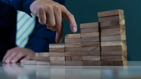 A businessman puts a wooden block in steps on it. The concept of growth and success plan