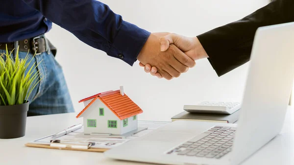 The sales representative shakes the customer\'s hand and offers a home purchase contract to purchase the current home and lease. Sales agents offer house projects, ideas to buy and rent.