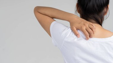 Ağır omuz ağrısı olan ve ellerini beyaz arka plan tıbbi konseptiyle kaplayan bir kadın..