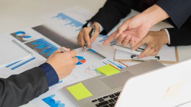 İş kadınları ve erkekler finansal raporları okuyarak, Asyalı kadın ve erkek yöneticilerin müzakere kararlarını tartıştıkları, analiz ettikleri ve hesapladıkları grafik belgelerini inceliyorlar. İşte bir takım gibi çalışın.